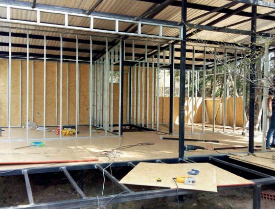 Las fundaciones de las columnas se realizaron con columnas metálicas empotradas en bases de hormigón. Para nivelar el piso se decide elevarlo por medio de estructura metálica y piso flotante instalado sobre paneles de OSB.